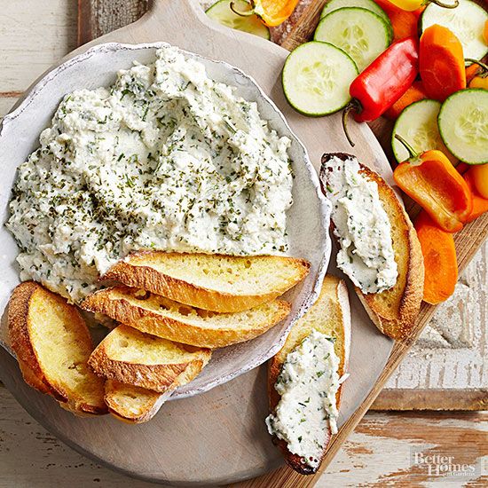 a platter with bread, vegetables and dip on it