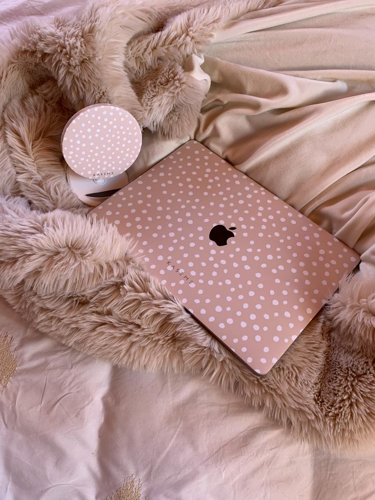 an apple laptop sitting on top of a bed covered in white polka dot blankets and pillows