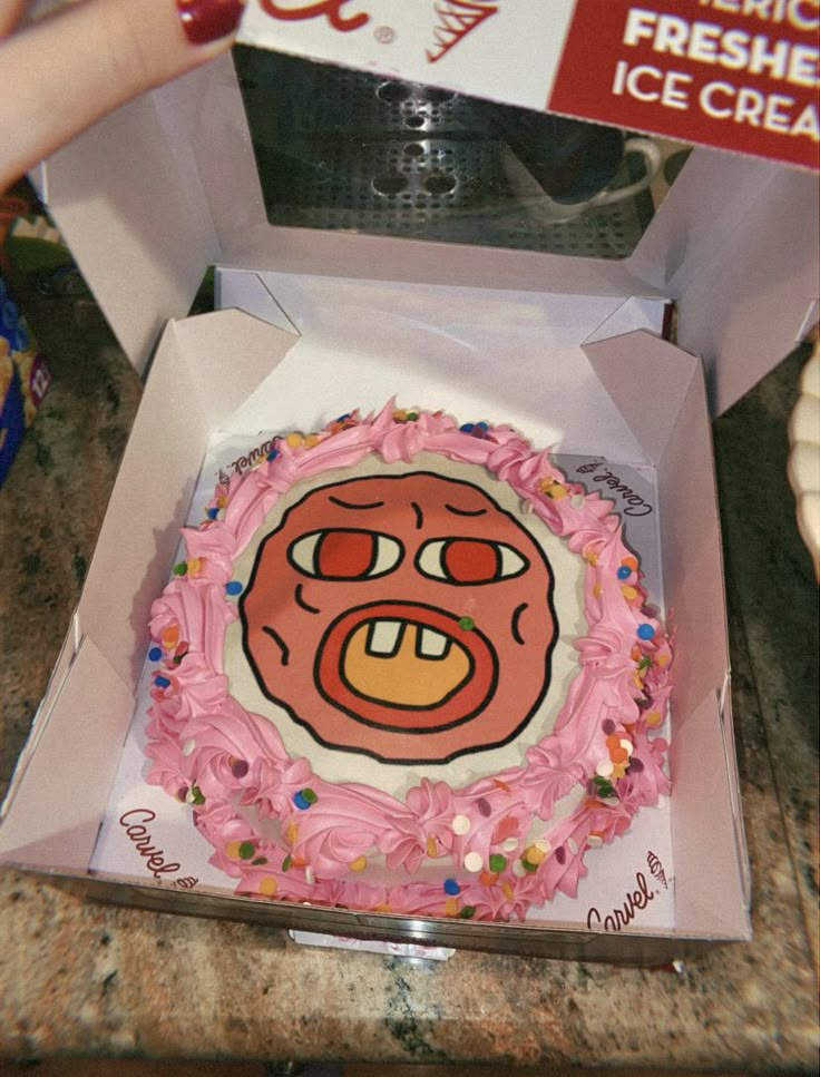 a cake in a box with pink frosting and sprinkles on it