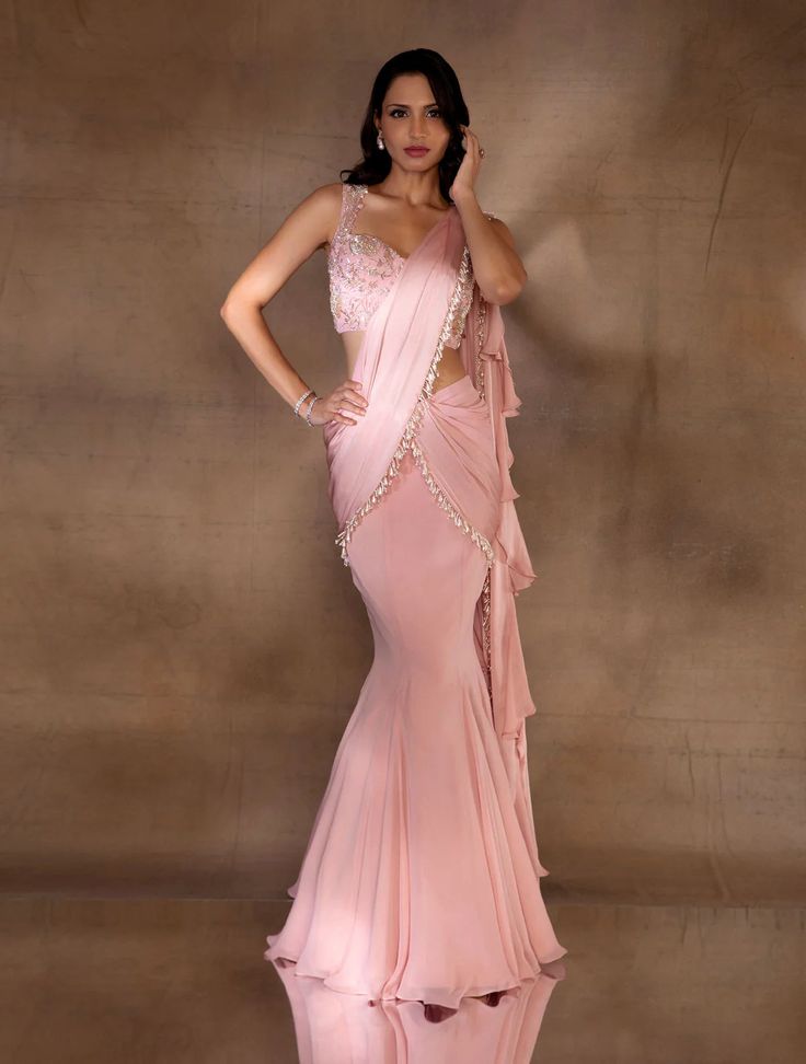 Soft pink fishtial sari with an attached georgette & satin georgette pallu hand embellished with dangling glass bugles & ivory pearls, with a satin georgette ruffle pallu. Paired with a corset crop hand embellished with champagne florals & an open embellished tie back.From Shloka Khialani's Winter Sun collection.DELIVERY TIMEPlease allow 6-8 weeks for your outfit to arrive.FABRIC DETAILSGeorgette, Satin Georgette, Net, CrepeProfessional cleaning only. Luxury Pink Saree With Gota Work, Pink Saree With Mirror Work, Elegant Draped Pink Lehenga, Glamorous Pre-draped Saree With Ruffles For Reception, Glamorous Ruffled Pre-draped Saree For Reception, Elegant Pink Organza Pre-draped Saree, Silk Pink Pre-draped Saree For Reception, Silk Pre-draped Pink Saree For Reception, Pink Silk Pre-draped Saree For Reception