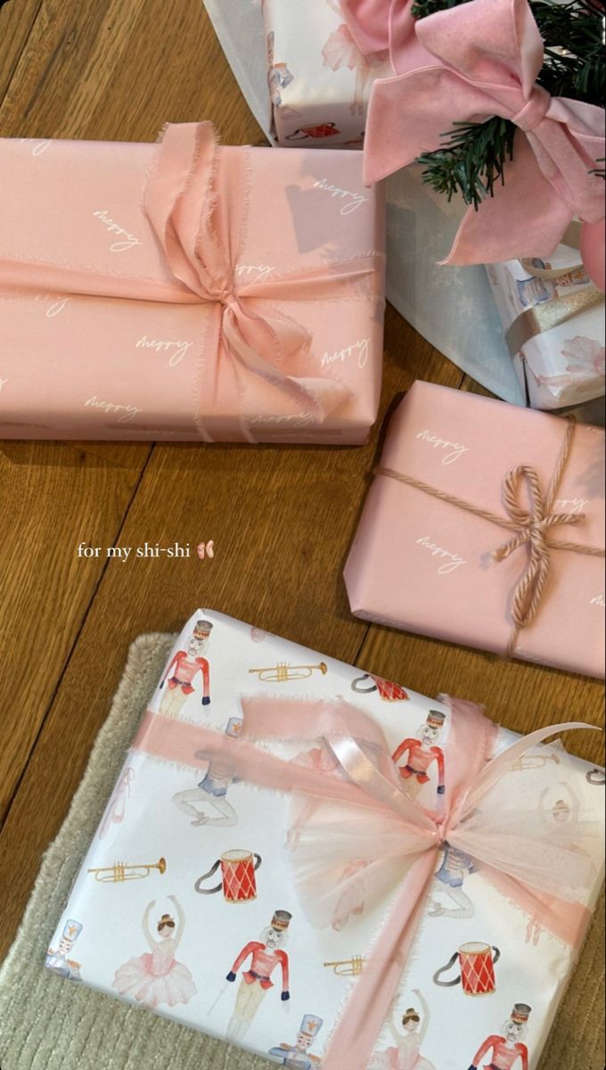 presents wrapped in pink and white paper with bows on them sitting on a wooden table