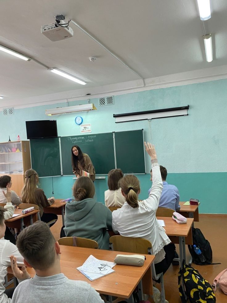 a group of people sitting at desks in front of a blackboard