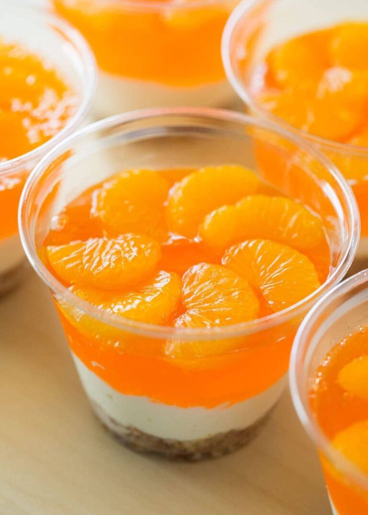 small cups filled with oranges on top of a wooden table next to each other