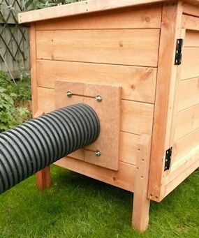 a large black hose is attached to the side of a wooden birdhouse on grass