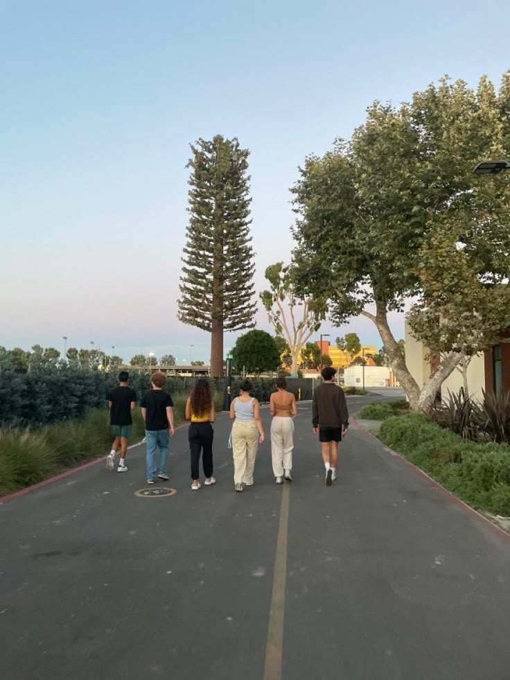 four people walking down the road with trees in the background