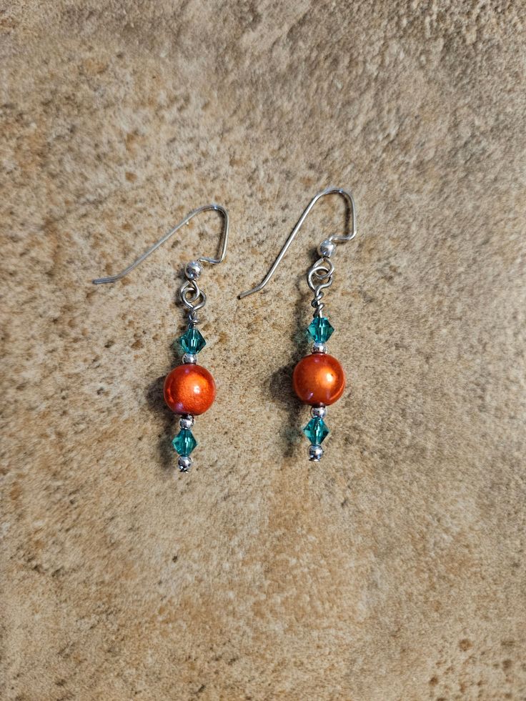 This pair is made with sterling silver fishhook, orange center bead and green Swarovski crystals. Orange Jewelry With Dangling Beads, Adjustable Orange Tiny Beads Earrings, Orange Sterling Silver Jewelry With Round Beads, Orange Czech Glass Jewelry With Ear Wire, Orange Drop Earrings With Dangling Beads, Orange Dangle Earrings With Tiny Beads, Elegant Orange Czech Glass Jewelry, Nickel-free Orange Beaded Dangle Earrings, Beaded Jewelry Diy