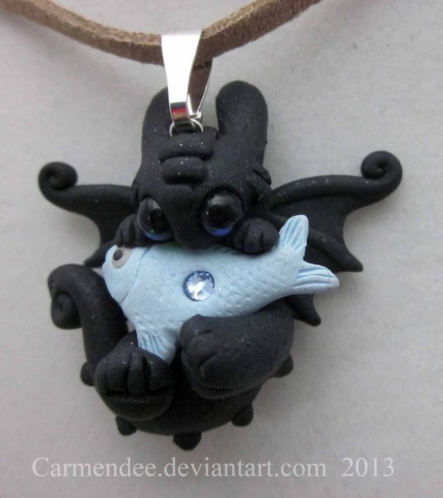 a necklace with a black dragon holding a small blue fish on it's back