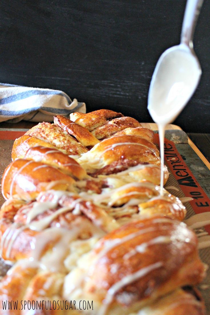 a spoon drizzling melted cheese on top of some croissants