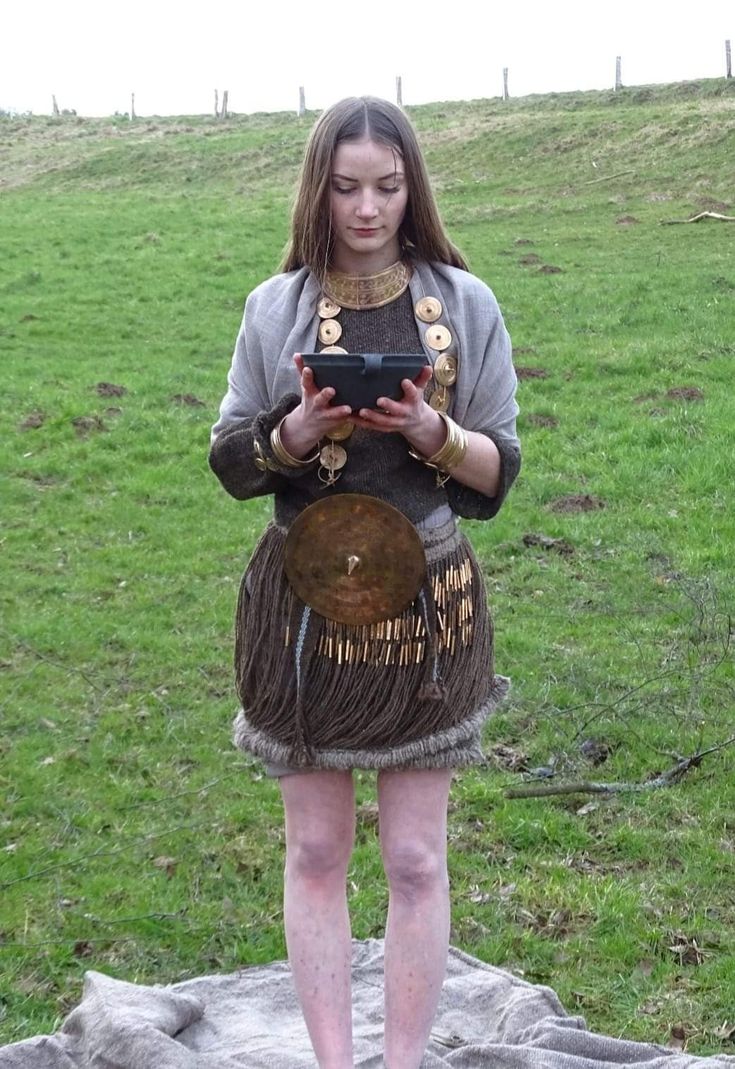 a young woman dressed in native garb using a cell phone while standing on a rock