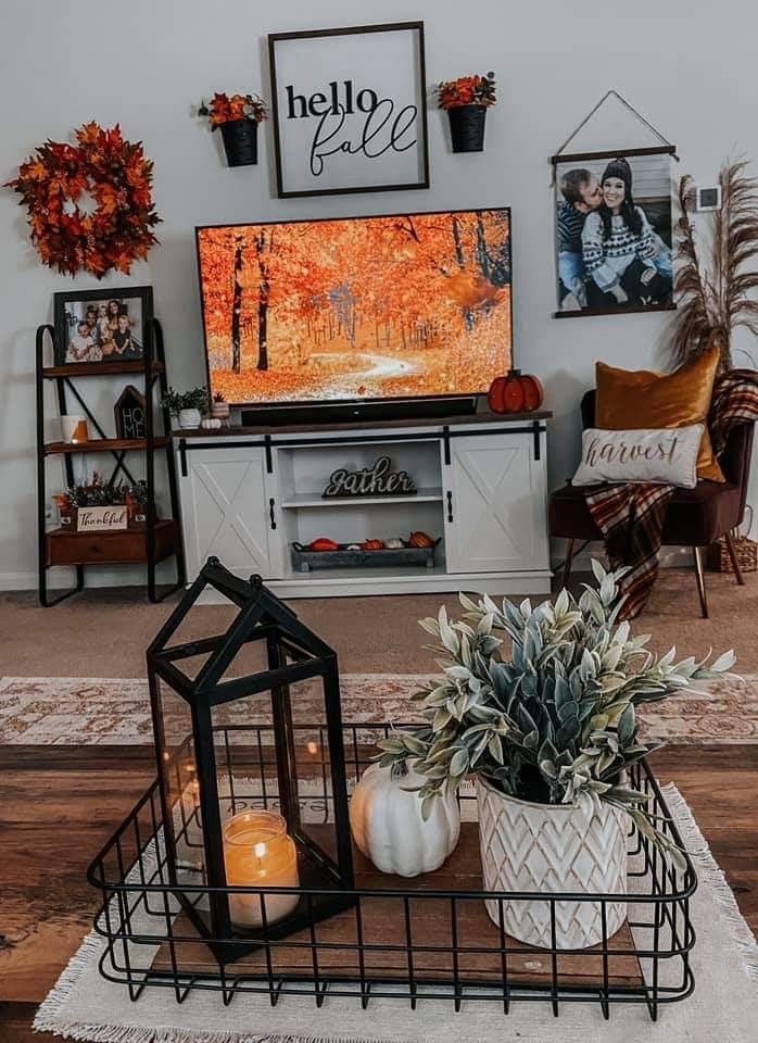 the living room is decorated for fall with pumpkins, candles and pictures on the wall