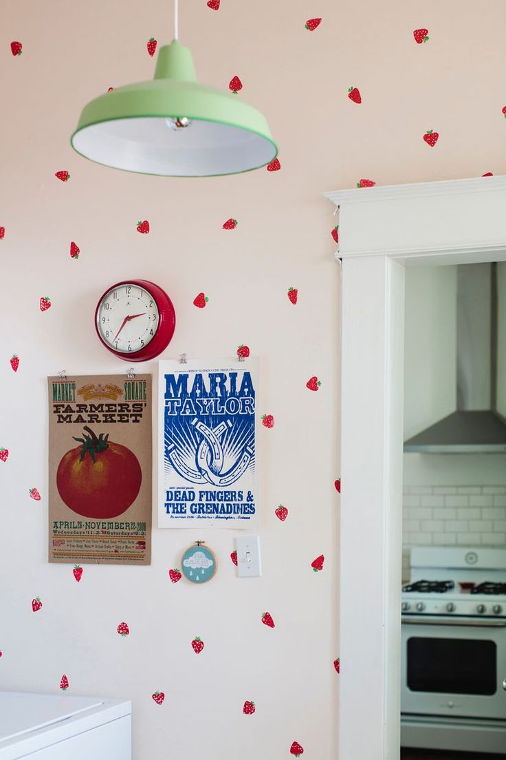 a kitchen wall with red flowers on it and a green light hanging from the ceiling