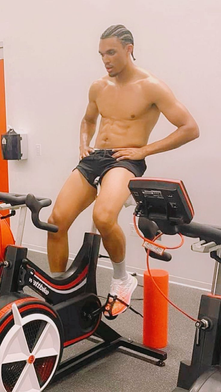 a man sitting on an exercise bike in a room with orange and black poles around him