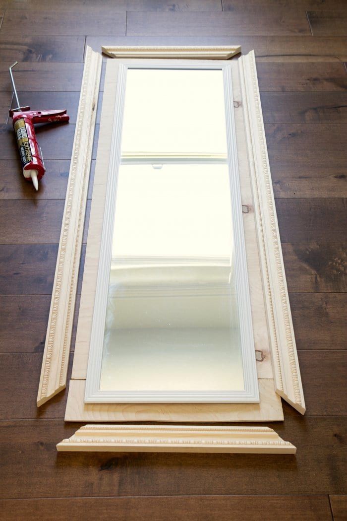 a mirror sitting on top of a hard wood floor next to a brush and glue