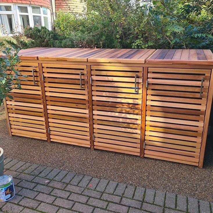 a large wooden cabinet sitting on top of a brick sidewalk next to a potted plant