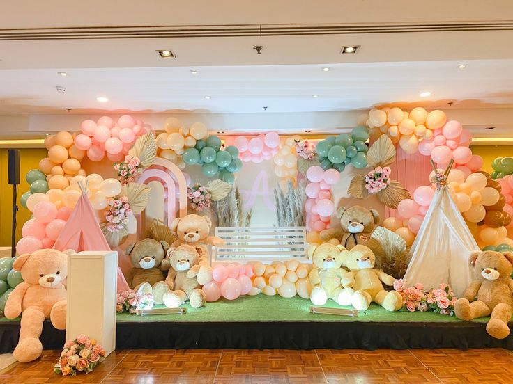 there are many balloons and teddy bears on the stage set up for a baby's first birthday party