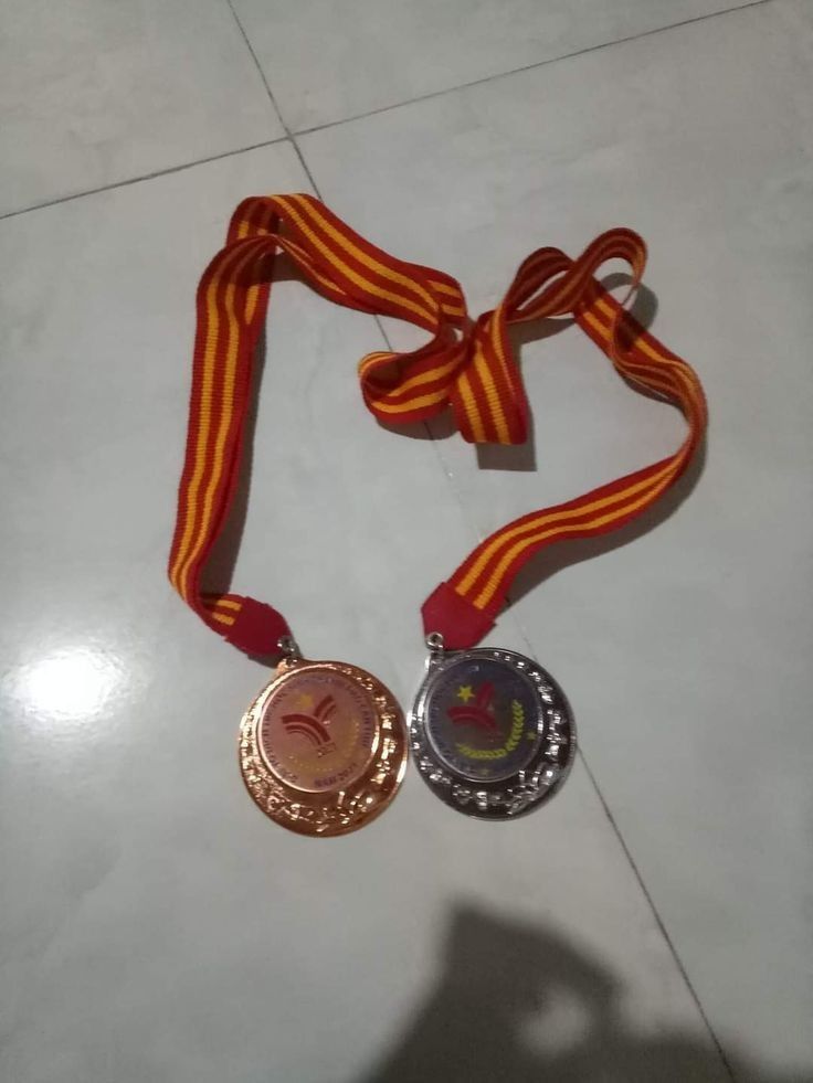 two medals are laying on the floor next to each other and one has a ribbon around it