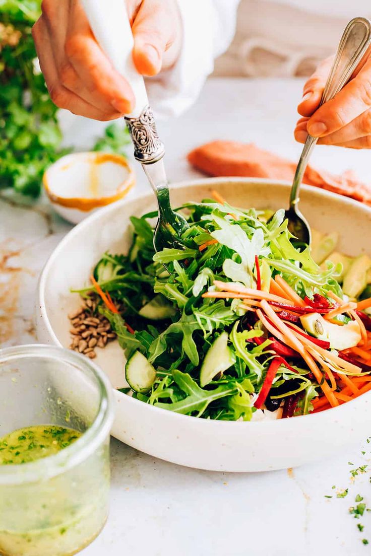 a person is cutting into a salad in a bowl