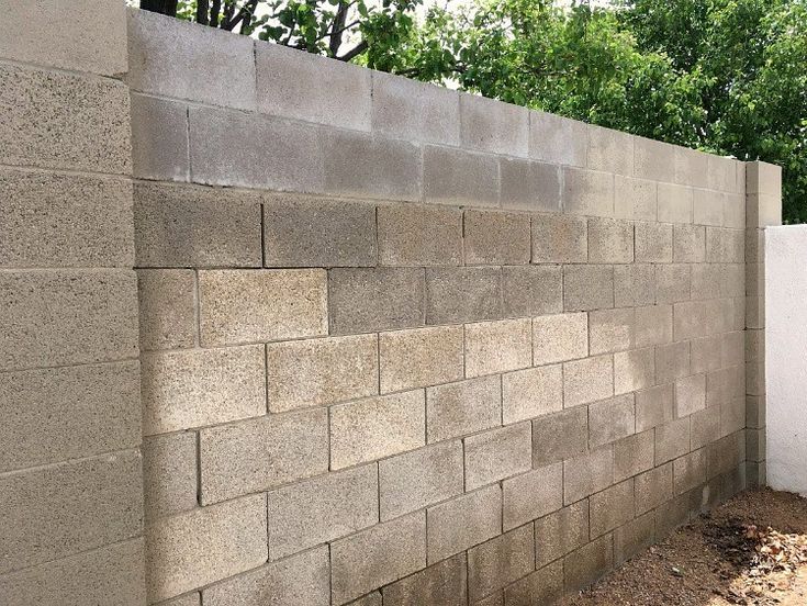 a concrete block wall next to a white fence