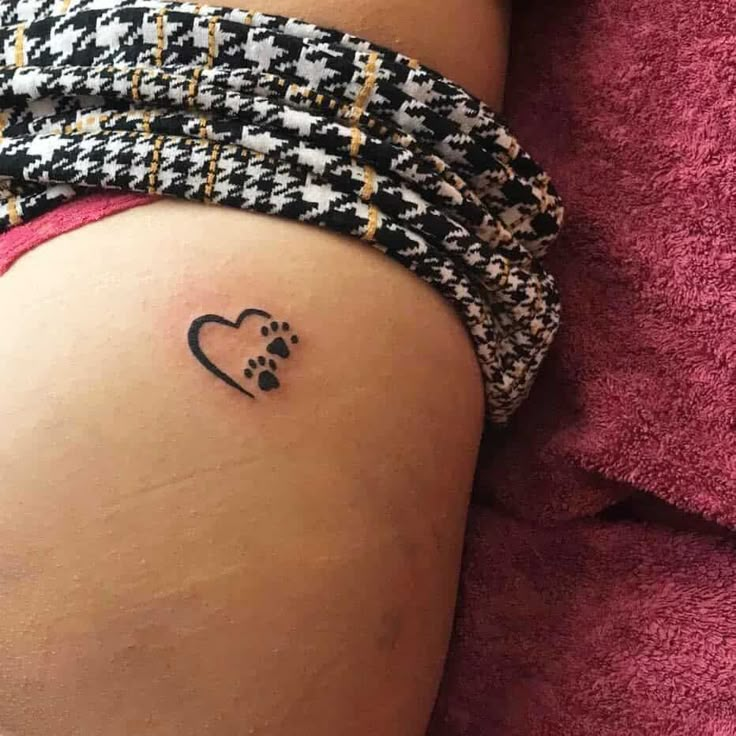 a small dog paw tattoo on the side of a woman's thigh and leg