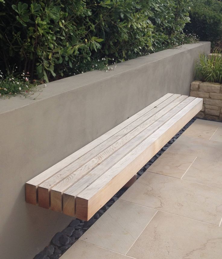 a wooden bench sitting next to a cement wall