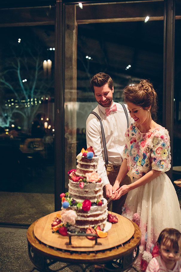 a bride and groom are cutting their wedding cake at the reception table with small children