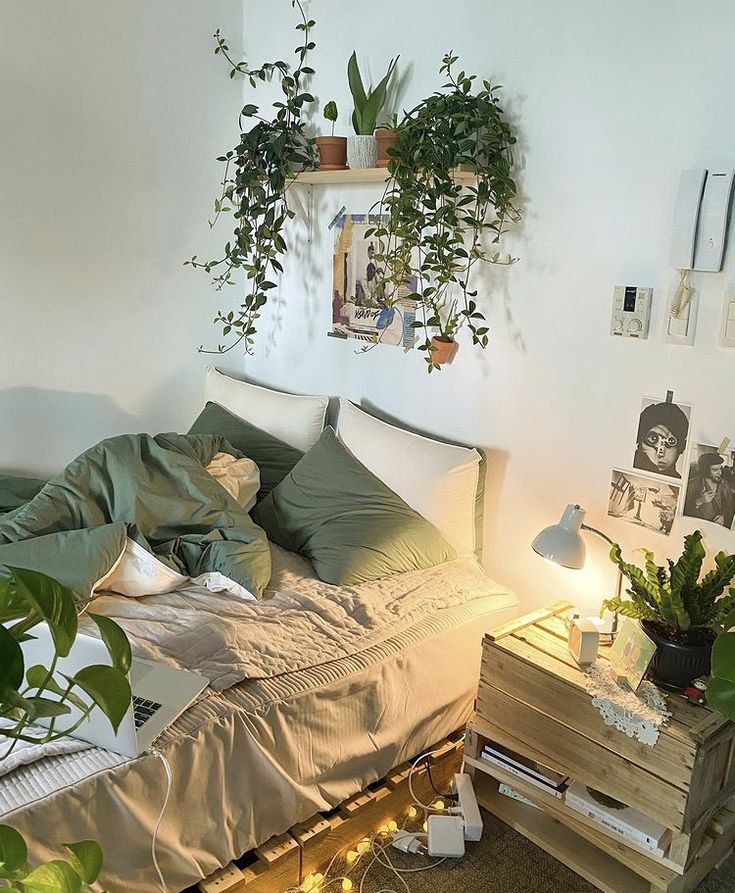 an unmade bed with lots of plants on the headboard and side tables next to it