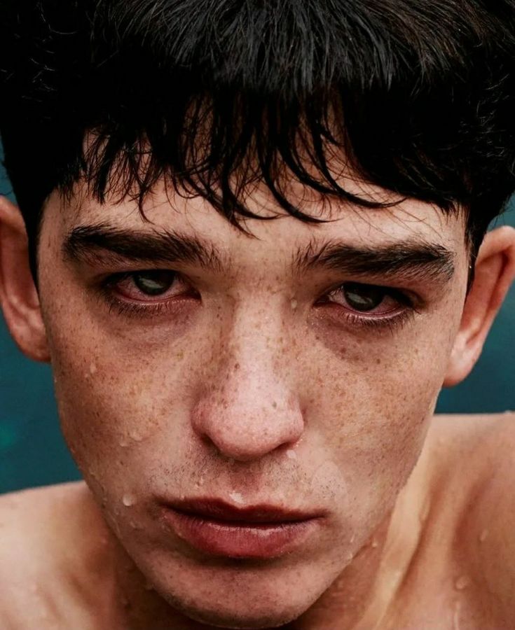 a young man with freckles on his face looking at the camera and frowning