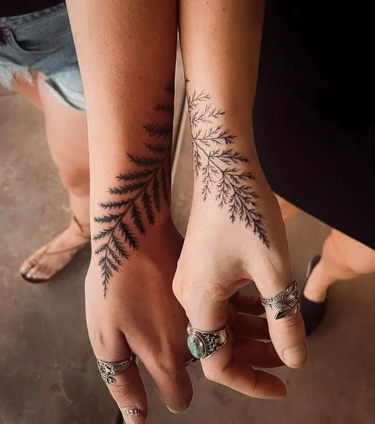 two people with tattoos on their hands and one is holding the other's hand