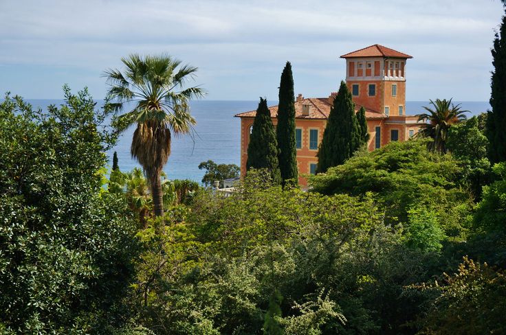 an old building is surrounded by greenery and trees with the ocean in the background