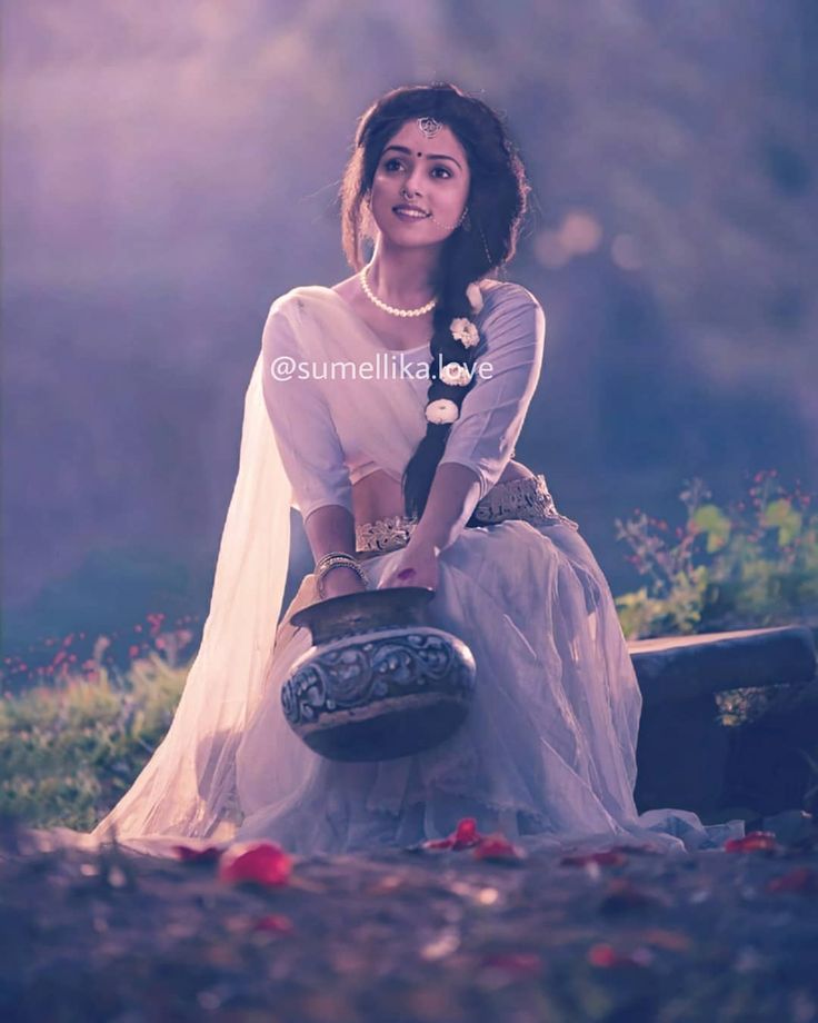 a woman is sitting on a bench with a pot in her hand and flowers around her