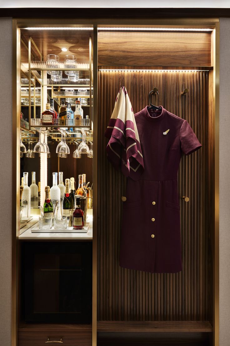 a display case with bottles and wine glasses on the wall, in front of it