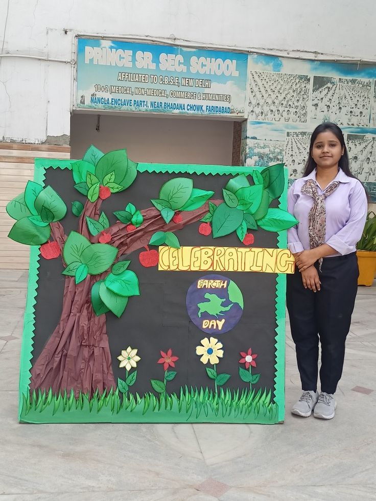 a woman standing in front of a bulletin board decorated with leaves and flowers on it