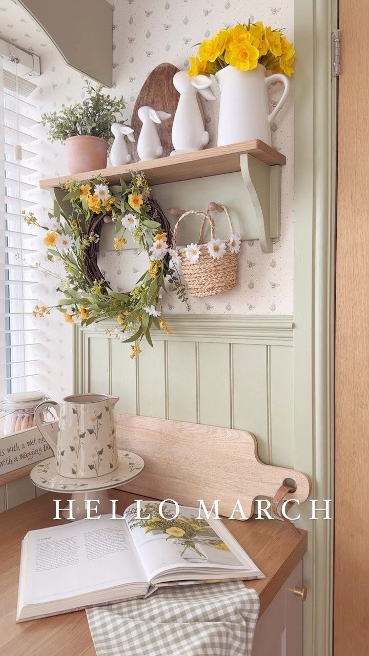 there is a shelf with flowers on it next to a book and coffee mugs