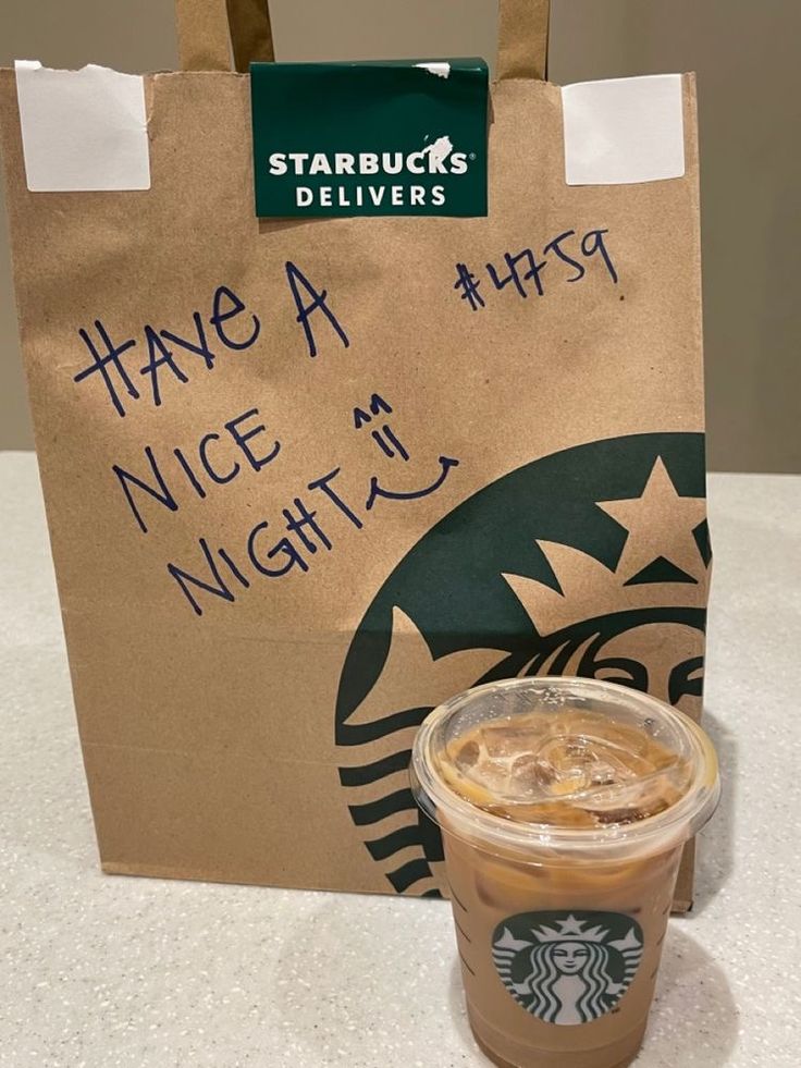 there is a starbucks drink in the cup next to a paper bag that says have a nice night