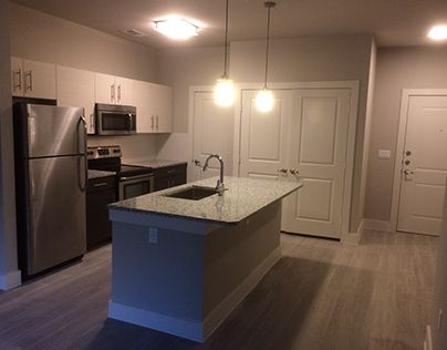 an empty kitchen with stainless steel appliances and wood flooring in the middle of it