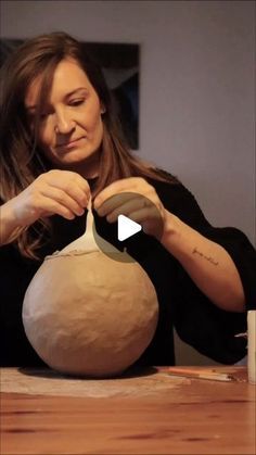 a woman is making a vase out of clay