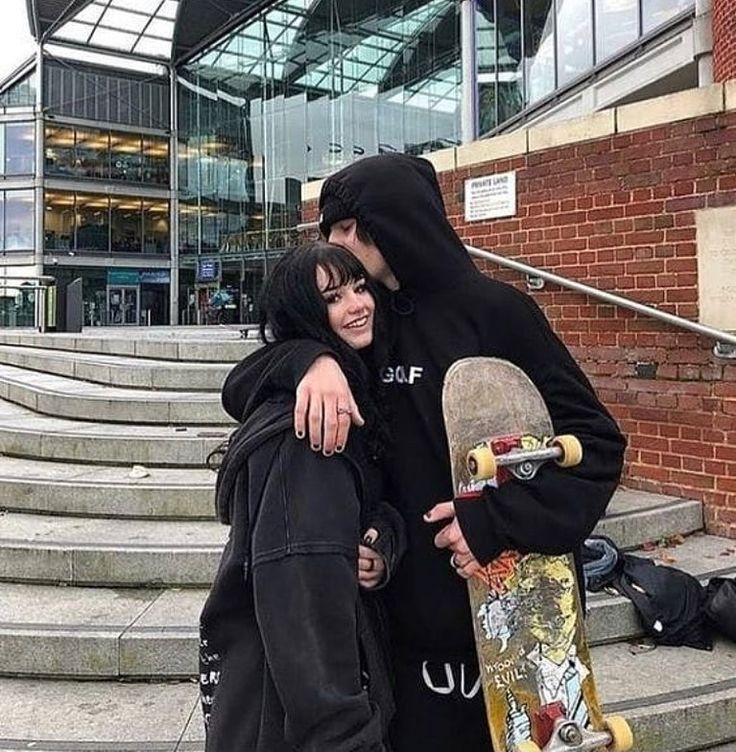 two people standing next to each other with skateboards in their hands and one person wearing a black hoodie