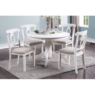 a white table with four chairs and a rug on the floor in front of it