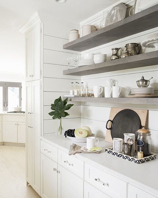 a white kitchen with open shelving on the wall