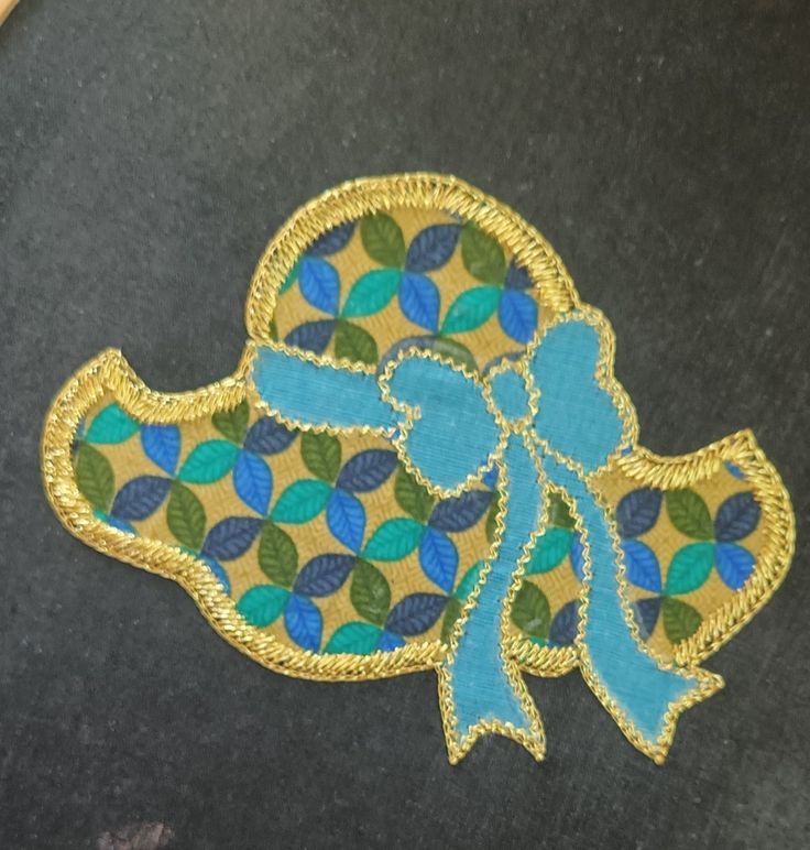 a close up of a piece of cloth with a blue bow on it and green leaves