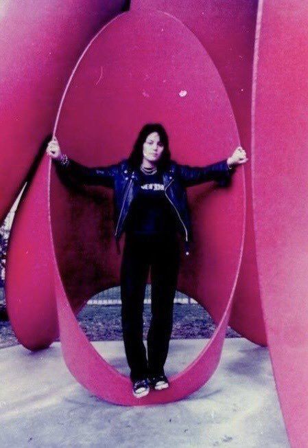 a woman standing in front of a giant pink object with her arms out and hands on her hips