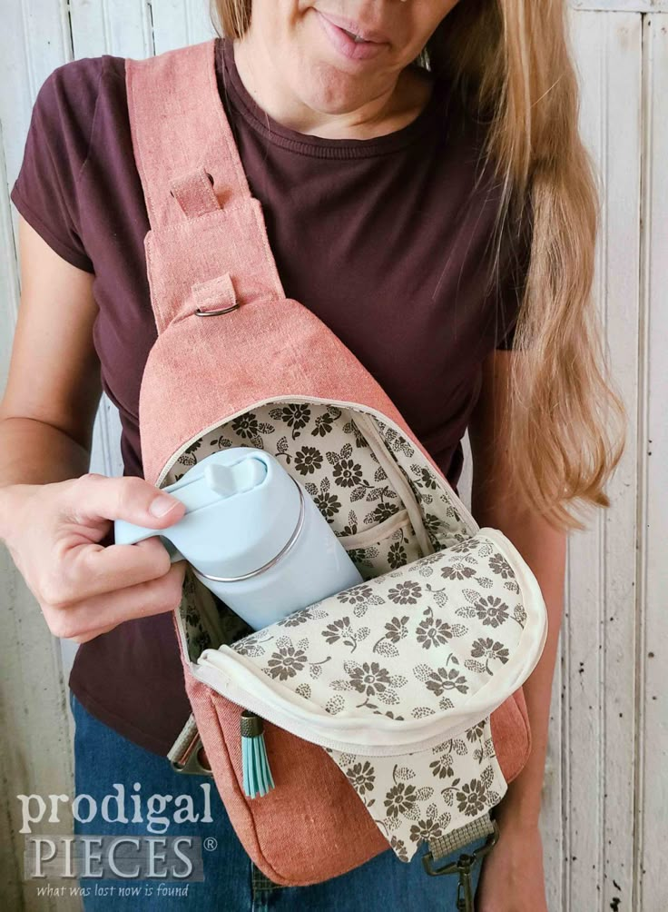 a woman is holding a small backpack in her hands and she has an insulated cup in the pocket