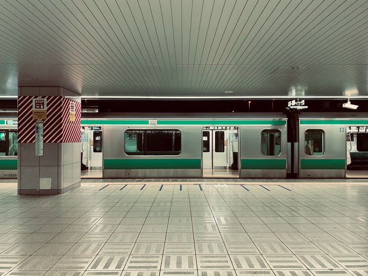 an empty subway station with green and white trains