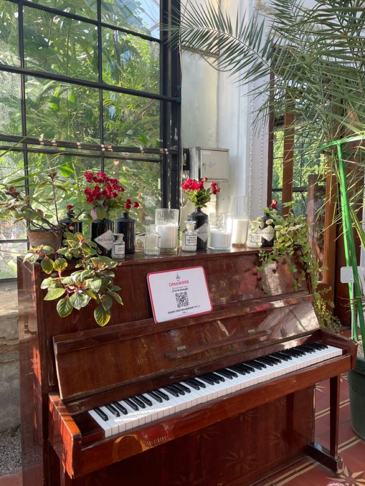 an old piano sitting in front of a window filled with potted plants