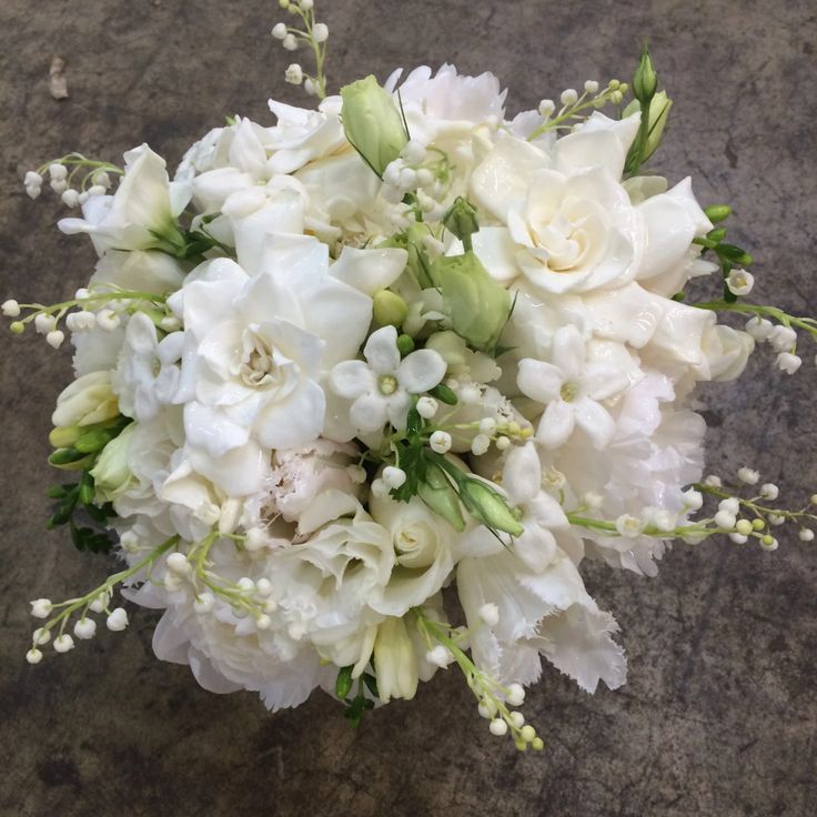 a bouquet of white flowers sitting on top of a stone floor next to a wall