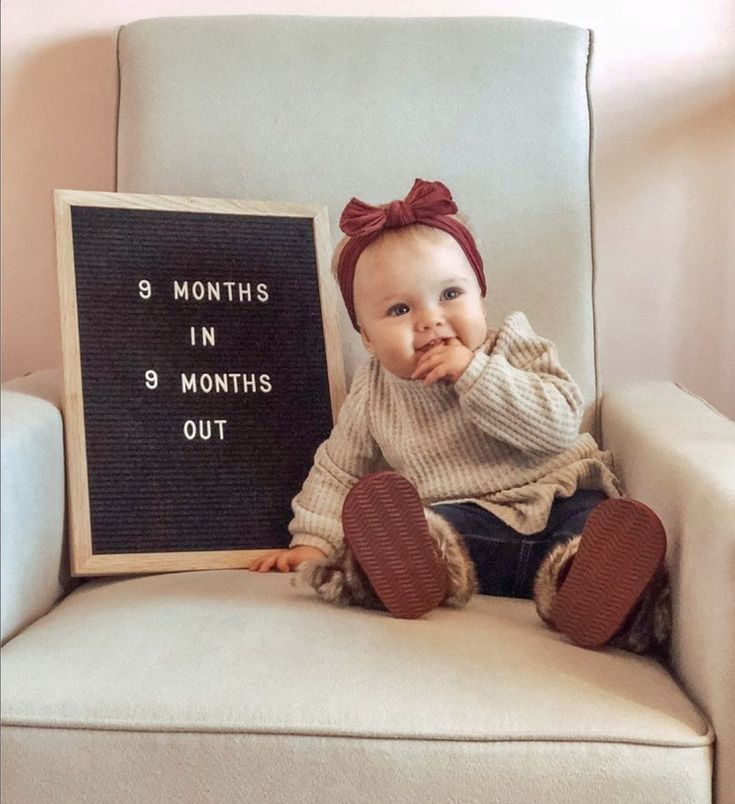 a baby sitting in a chair with a sign that says 8 months in 3 months out