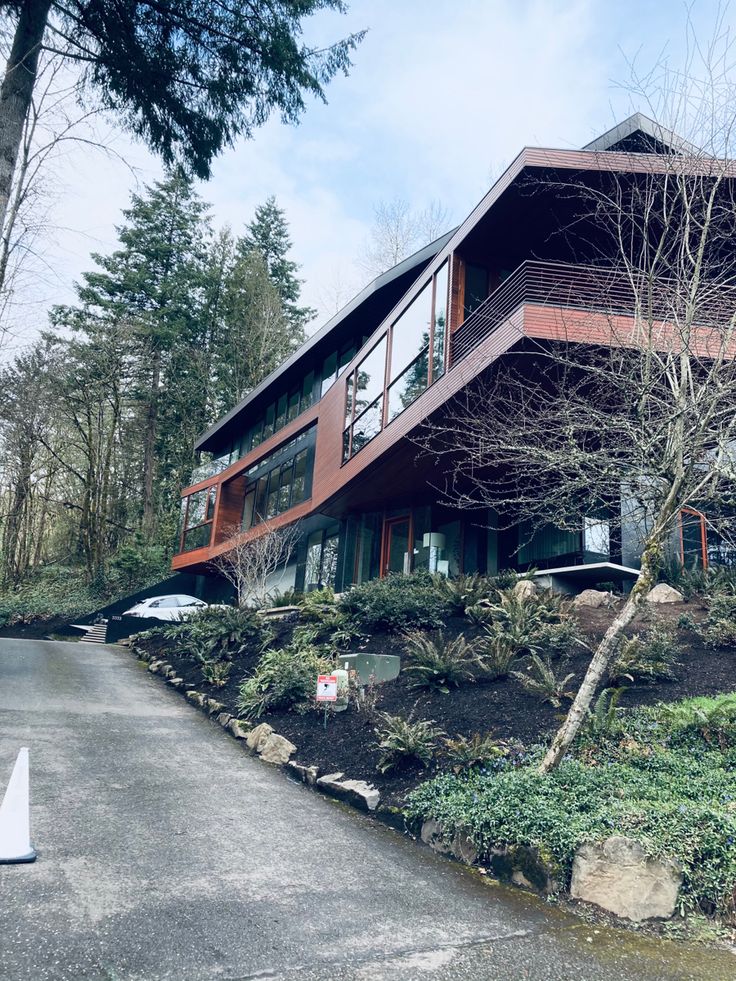 a large house sitting on top of a lush green hillside next to a parking lot