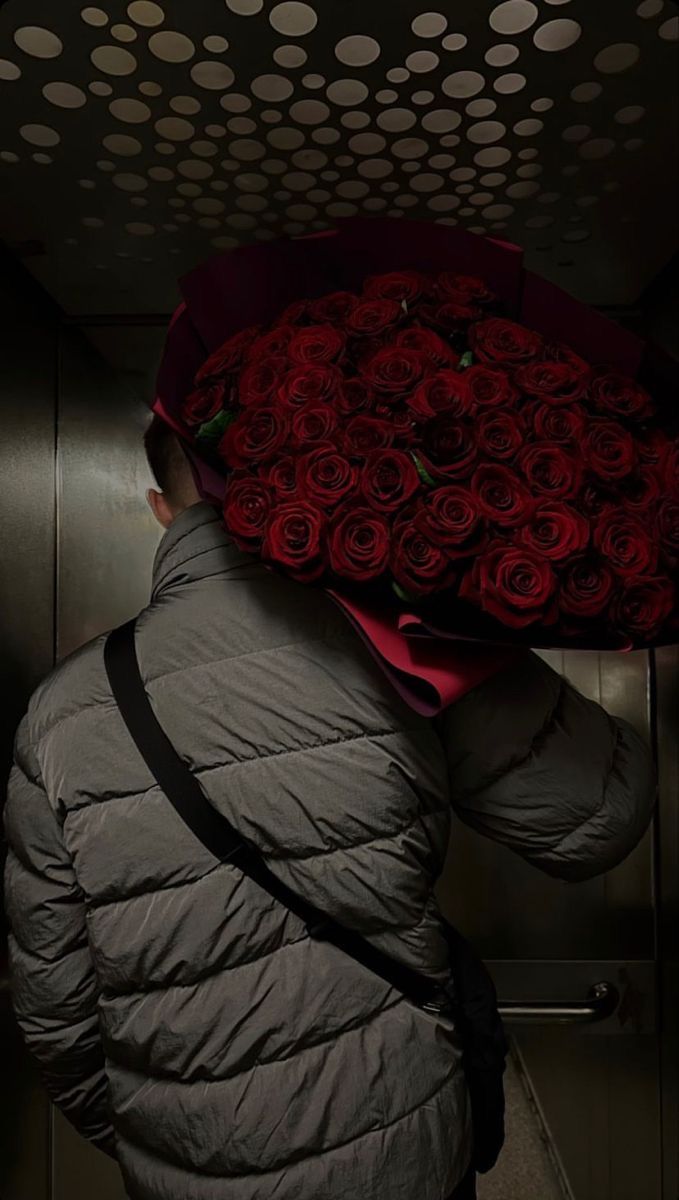 a person with a bunch of red roses on their head and jacket over their head