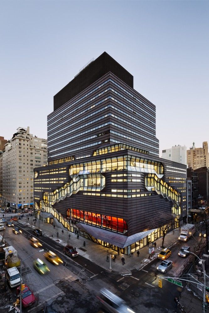 a large building with many windows and lights on it's side in the city