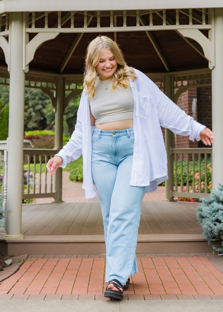 a woman in light blue jeans and a white cardigan